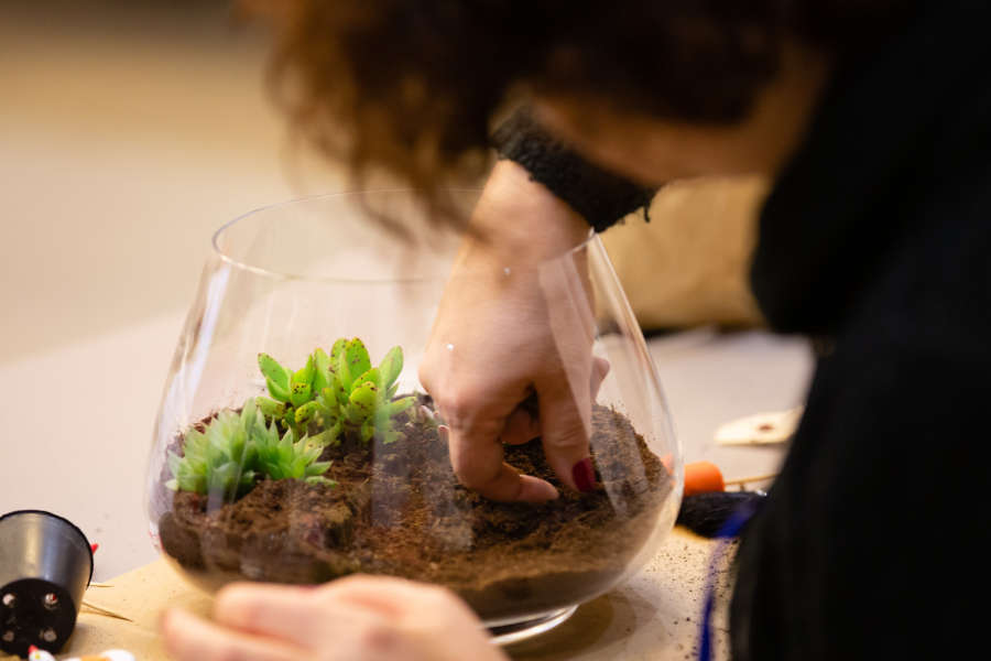 Creazione pratica di un terrarium con piante e terriccio all'interno di una boule di vetro durante il workshop a Cuneo.