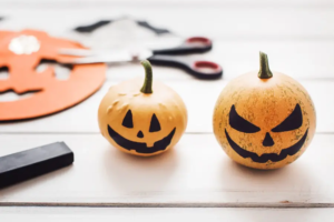 Zucche decorate a mano per Halloween con volti sorridenti e mostruosi, usate come anteprima per il laboratorio per bambini da Garden Roagna Vivai.